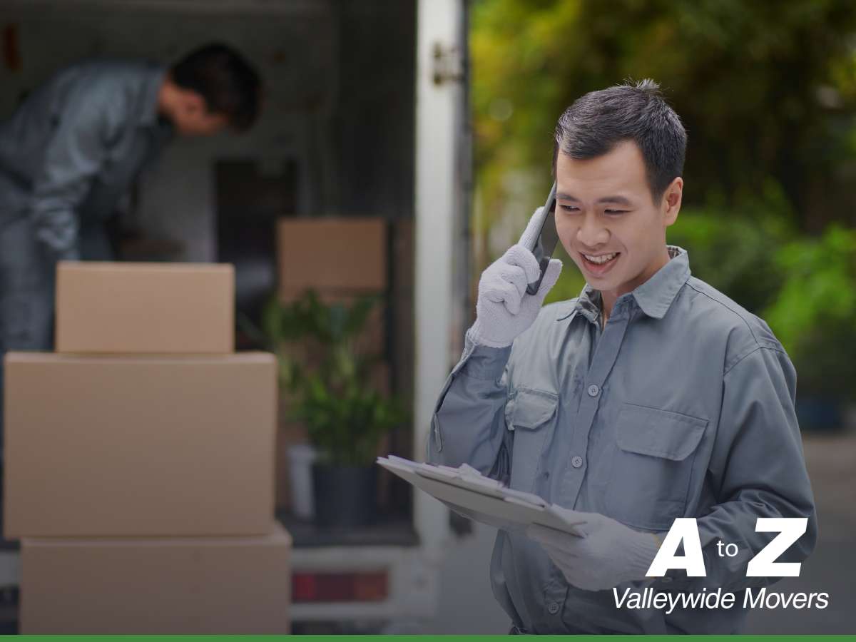 Moving company professionals efficiently coordinating a move, with one worker organizing boxes and another on a call.