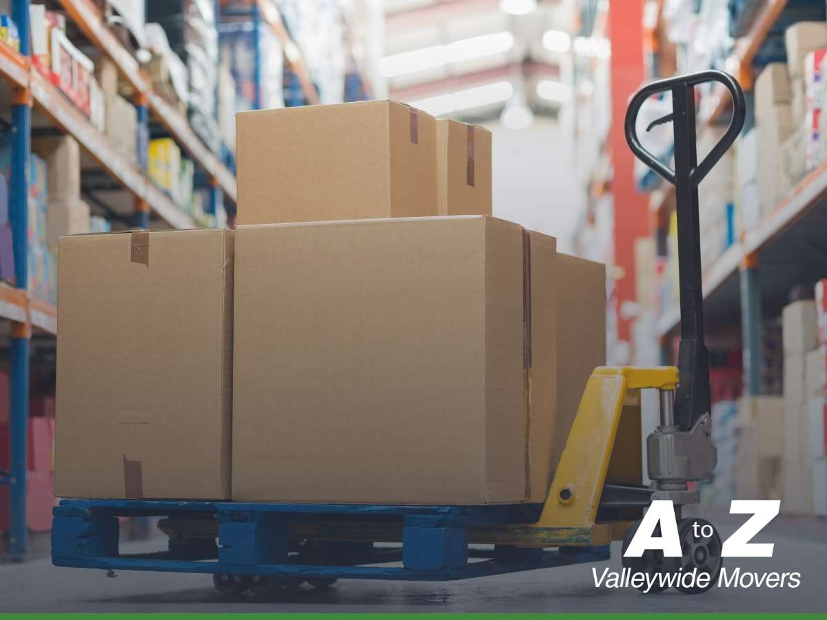 Stacked moving boxes on a pallet jack in a warehouse, representing storage moving services.